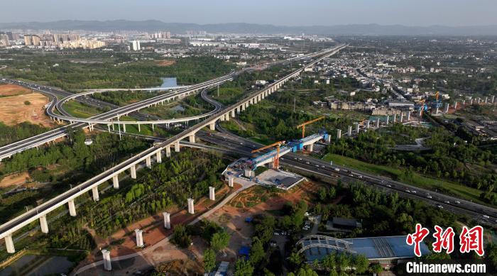 航拍正在建設(shè)的跨越成都繞城高速公路連續(xù)梁施工現(xiàn)場，旁邊依次為已運(yùn)營的成渝高速鐵路和機(jī)場高速公路?！⒅铱?攝