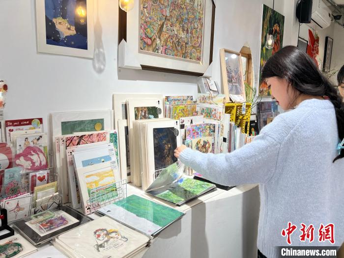 圖為藝術(shù)品商店內(nèi)，顧客挑選插畫作品。　鐘旖 攝