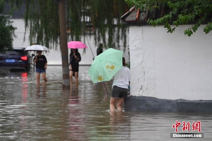 7月31日，市民行走在雨中的北京房山區(qū)瓦窯頭村。北京市氣象臺(tái)當(dāng)日10時(shí)發(fā)布分區(qū)域暴雨紅色預(yù)警信號(hào)。北京市水文總站發(fā)布洪水紅色預(yù)警，預(yù)計(jì)當(dāng)日12時(shí)至14時(shí)，房山區(qū)大石河流域?qū)⒊霈F(xiàn)紅色預(yù)警標(biāo)準(zhǔn)洪水。<a target='_blank' href='/'><p  align=