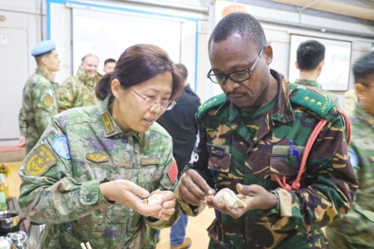 圖為維和官兵與外軍人員共同包餃子。胡光明攝