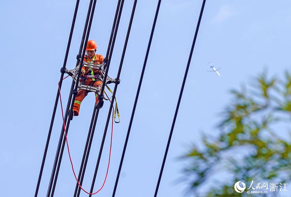 3月11日，在浙江省諸暨市河上鎮(zhèn)，浙江省送變電工程有限公司檢修人員在高空的導(dǎo)線上進行線路檢修維護。人民網(wǎng) 章勇濤攝