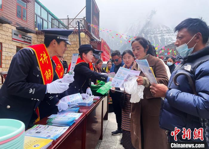 圖為山南玉麥邊境派出所民警為轄區(qū)群眾發(fā)放法律知識宣傳單。　鐘鑫 　攝