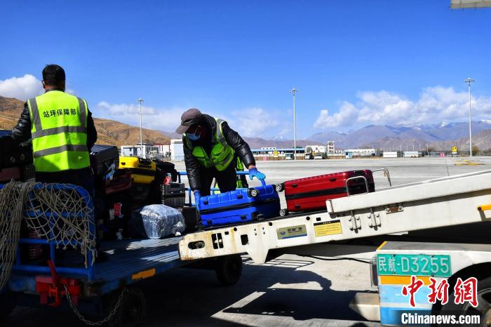 圖為機(jī)場工作人員傳送旅客行李箱?！≈芎?攝