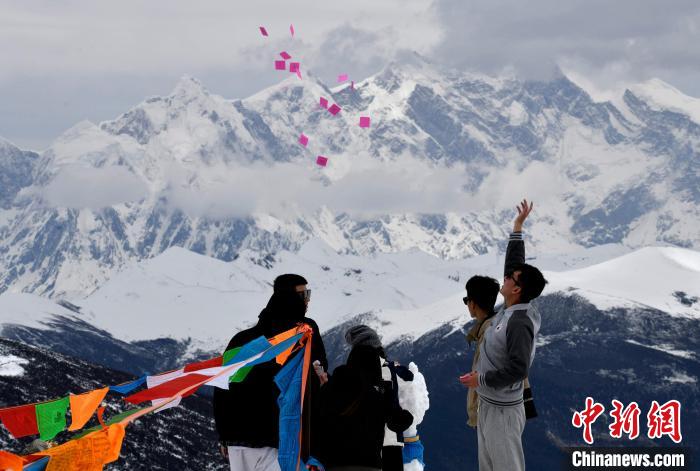 圖為5月14日，游客在西藏林芝色季拉山觀景臺拋灑“隆達(dá)”(風(fēng)馬旗，藏族民眾的一種祈福方式)?！±盍?攝