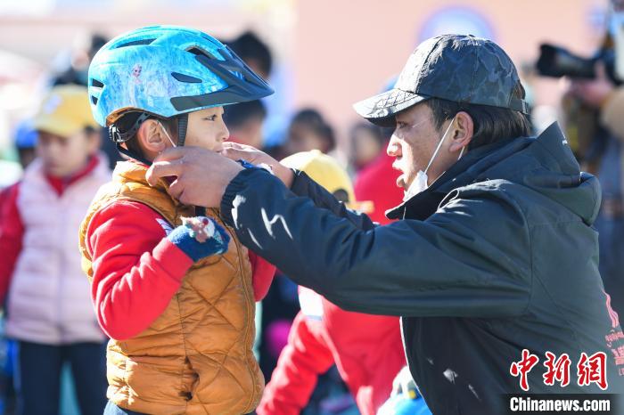 圖為拉薩市實(shí)驗(yàn)幼兒園孩子在教練的幫助下穿戴頭盔?！『闻罾?攝