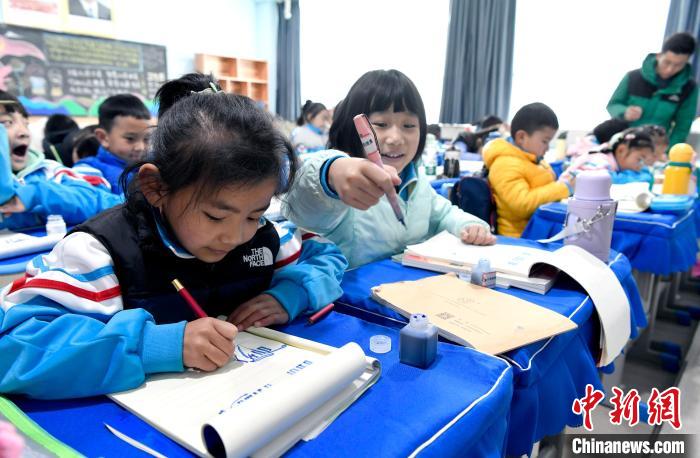 3月14日，西藏拉薩市第一小學一年級六班學生白瑪朗珍(圖左)在藏語文課上書寫藏文。　李林 攝