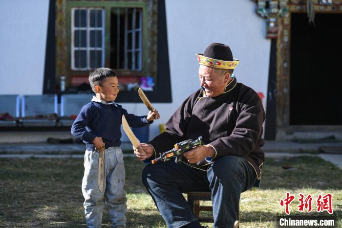 圖為米林縣扎西繞登鄉(xiāng)彩門村64歲的洛桑帶著孫子巴桑在院子的草地上玩耍。　何蓬磊 攝